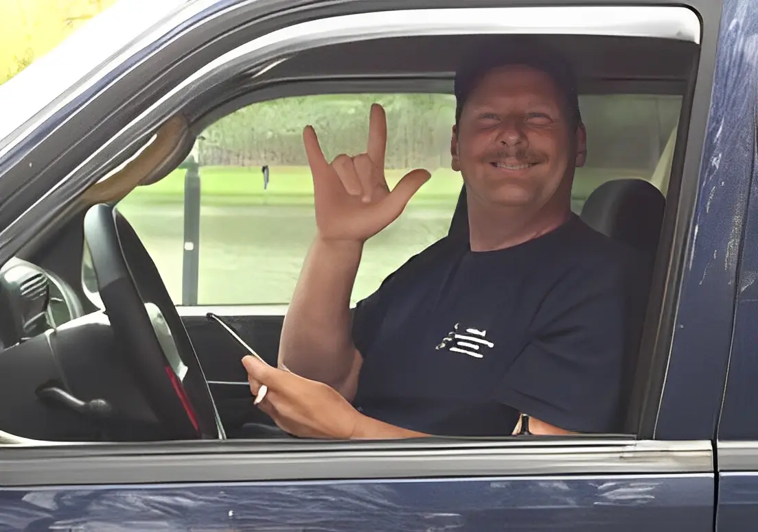 Person smiling and gesturing in parked vehicle. Person smiling and gesturing in parked vehicle.